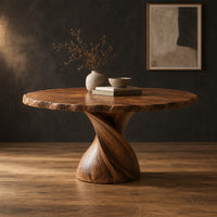 Circular dining table with twisted pedestal base and rippled edge in a dark studio against a charcoal plaster wall