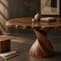 Corner detail of circular dining table with twisted pedestal base and rippled edge beside wood, brass and linen samples