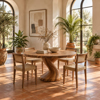 Round dining table on a single twisted pedestal in a bright dining room with arched windows and plants