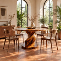 Round dining table with a spiral twisted pedestal on a thick disc base in a bright dining room with arched windows and plants
