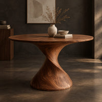 Corner detail of round dining table on a twisted spiral pedestal beside wood, brass and linen samples