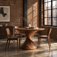 Round dining table on a twisted spiral pedestal in an industrial loft dining room with exposed brick