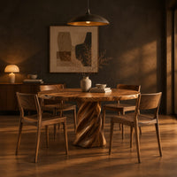Round dining table with a twisted spiral pedestal base in a dark dining room at golden hour