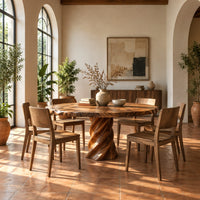 Round dining table with a twisted spiral pedestal base in a bright dining room with arched windows and plants