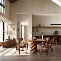 Round dining table with a twisted spiral pedestal base in a bright open plan dining room