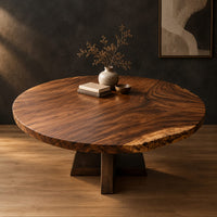 Circular wood table top with swirling grain and one natural edge in a dark studio against a charcoal plaster wall