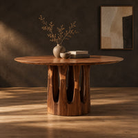 Round pedestal dining table with tall arched slots in the base in a dark studio against a charcoal plaster wall