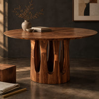 Corner detail of round pedestal dining table with tall arched slots in the base beside wood, brass and linen samples