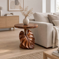 Round side table on a pedestal carved like a large leaf in a Scandinavian living room with white walls