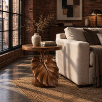 Round side table on a pedestal carved like a large leaf in an industrial loft living room with exposed brick