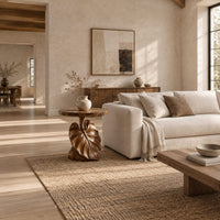 Round side table on a pedestal carved like a large leaf in a bright open plan living room