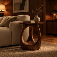 Round side table with an open teardrop pedestal and a flared foot in an evening living room with walnut wall paneling