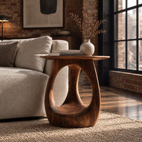 Round side table with an open teardrop pedestal and a flared foot in an industrial loft living room with exposed brick