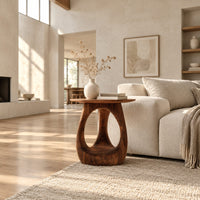 Round side table with an open teardrop pedestal and a flared foot in a bright open plan living room