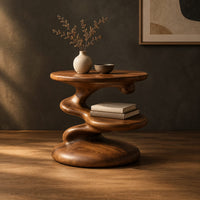 Circular side table with a spiral stem, middle shelf disc and wide base in a dark studio against a charcoal plaster wall
