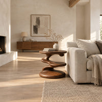 Circular side table with a spiral stem, middle shelf disc and wide base in a bright open plan living room