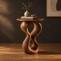 Round wood side table on a twisted figure eight pedestal in a dark studio against a charcoal plaster wall