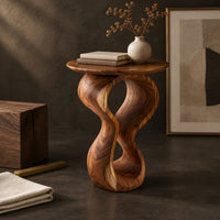 Corner detail of round wood side table on a twisted figure eight pedestal beside wood, brass and linen samples