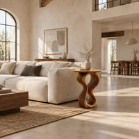 Round wood side table on a twisted figure eight pedestal in a bright open plan living room
