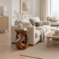 Round side table with a vase shaped base and twisting cutouts in a Scandinavian living room with white walls