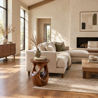 Round side table with a vase shaped base and twisting cutouts in a bright open plan living room