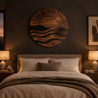 Round wall art of a sun setting over layered waves above a bed in a dusk lit bedroom