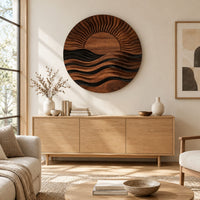 Round wall art of a sun setting over layered waves above a light oak sideboard in daylight