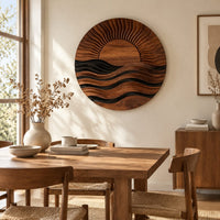 Round wall art of a sun setting over layered waves beside a dining table in natural light