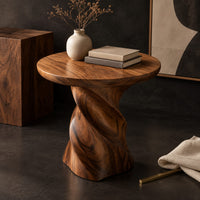 Corner detail of side table with a circular top on a twisted spiral pedestal beside wood, brass and linen samples