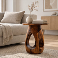 Round side table with teardrop cutouts in a pear shaped pedestal in a Scandinavian living room with white walls