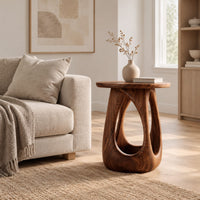 Side table with a round wood top and a bulging base with teardrop cutouts in a Scandinavian living room with white walls