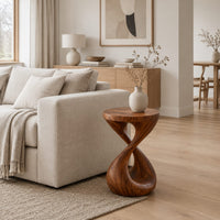 Side table with a circular top and a twisted figure eight pedestal base in a Scandinavian living room with white walls