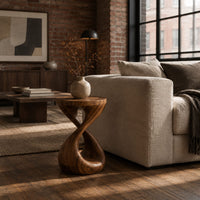 Side table with a circular top and a twisted figure eight pedestal base in an industrial loft living room with exposed brick