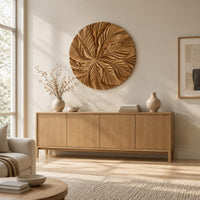Circular wood disc carved with overlapping leaves that radiate from the center above a light oak sideboard in daylight