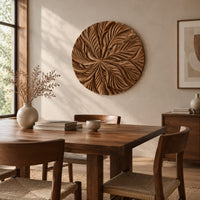 Circular wood disc carved with overlapping leaves that radiate from the center beside a dining table in natural light
