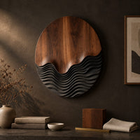 Detail of circular wood wall art with smooth grain above dark carved wave ridges beside wood, brass and linen samples