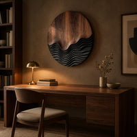 Circular wood wall art with smooth grain above dark carved wave ridges above a desk in a dark study corner