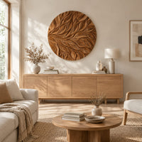 Circular wall art panel carved with sweeping layered leaves above a light oak sideboard in daylight