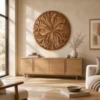 Round wood wall art with swirling carved petals in relief above a light oak sideboard in daylight