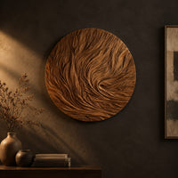 Round wooden wall relief with swirling carved ridges on a dark charcoal plaster wall