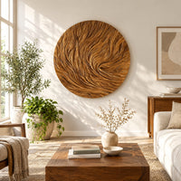 Round wooden wall relief with swirling carved ridges in a bright sunroom with green plants