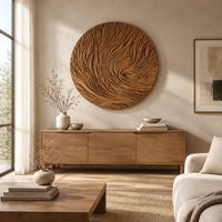Round wooden wall relief with swirling carved ridges above a light oak sideboard in daylight