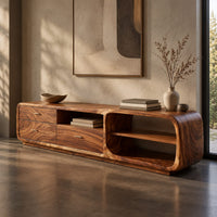 Corner detail of low rounded tv stand with three drawers and open shelves beside wood, brass and linen samples