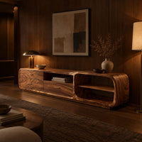 Low rounded tv stand with three drawers and open shelves in an evening living room with walnut wall paneling