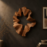 Ruffled wooden wall sculpture with an open star shaped center on a dark charcoal plaster wall