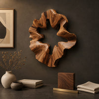 Detail of ruffled wooden wall sculpture with an open star shaped center beside wood, brass and linen samples