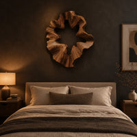 Ruffled wooden wall sculpture with an open star shaped center above a bed in a dusk lit bedroom