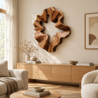 Ruffled wooden wall sculpture with an open star shaped center above a light oak sideboard in daylight