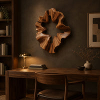 Ruffled wooden wall sculpture with an open star shaped center above a desk in a dark study corner