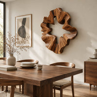 Ruffled wooden wall sculpture with an open star shaped center beside a dining table in natural light
